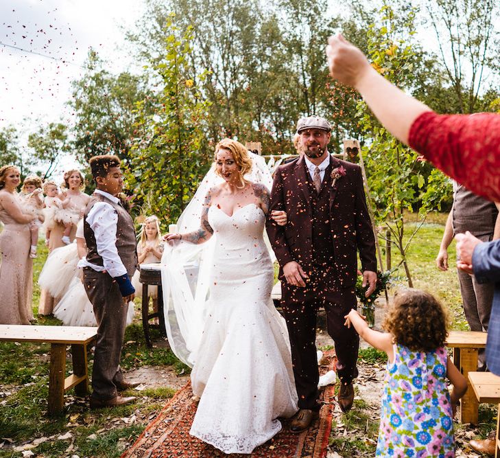 Confetti Moment | Bride in Strapless Sassi Holford Wedding Dress with Sweetheart Neckline | Groom in Burgundy Tweed Three Piece Suit | Edison Bulb Floral Installation at Kingsthorpe Lodge Barn Wedding | Johnny Dent Photography