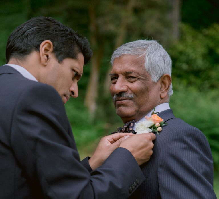 Groom fits father with bright floral buttonhole