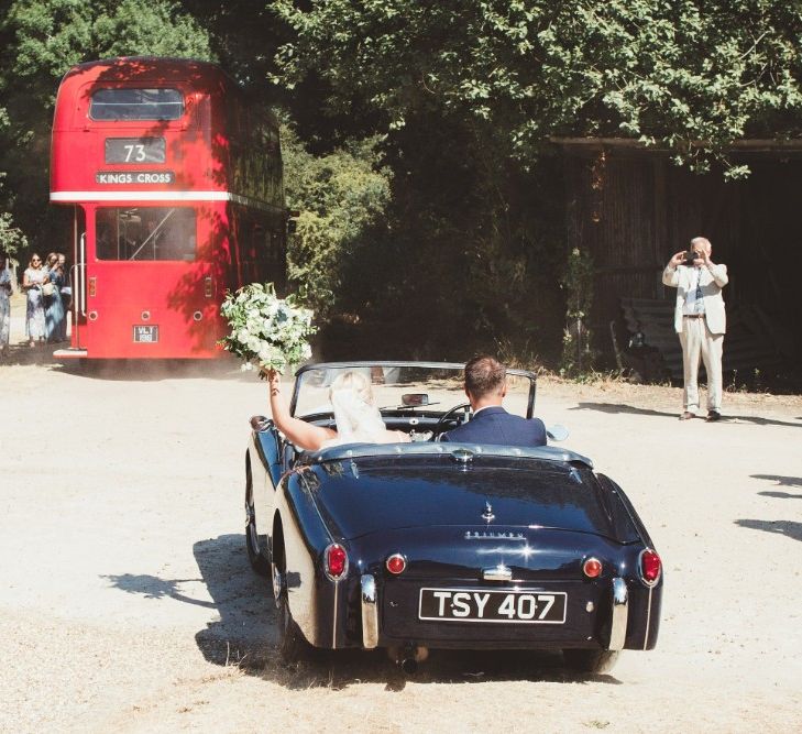 Bride and Groom in Vintage Car | Bride in Essense of Australia Dress with Spaghetti Straps and Fishtail | Floor Length Veil | Bridal Bouquet of White Flowers and Greenery | Groom in Blue Suit with White and Green Buttonhole | Red London Bus Wedding Transport | Quintessential English Country Wedding in Glass Marquee at Family Home | Maryanne Weddings Photography