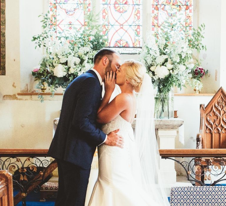 Wedding Ceremony | Bride in Essense of Australia Dress with Spaghetti Straps and Fishtail | Floor Length Veil | Groom in Blue Suit with White and Green Buttonhole | Large Glass Vases with White Flowers and Greenery | Quintessential English Country Wedding in Glass Marquee at Family Home | Maryanne Weddings Photography