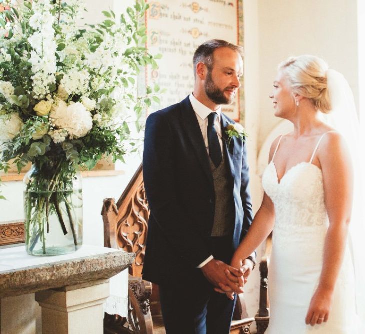 Wedding Ceremony | Bride in Essense of Australia Dress with Spaghetti Straps and Fishtail | Floor Length Veil | Groom in Blue Suit with White and Green Buttonhole | Large Glass Vase with White Flowers and Greenery | Quintessential English Country Wedding in Glass Marquee at Family Home | Maryanne Weddings Photography