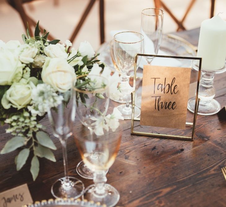 Table Number in Gold Frame | Gold Cutlery | Gold Rimmed Glassware | Table Arrangement of White Flowers and Greenery | Quintessential English Country Wedding in Glass Marquee at Family Home | Maryanne Weddings Photography