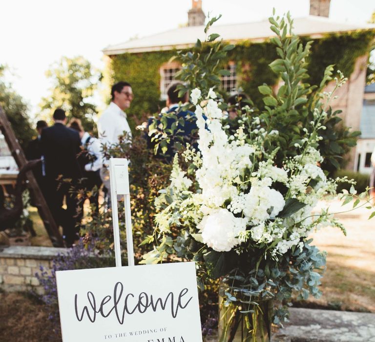 Welcome Sign | Glass Vase with White Flowers and Greenery | Quintessential English Country Wedding in Glass Marquee at Family Home | Maryanne Weddings Photography