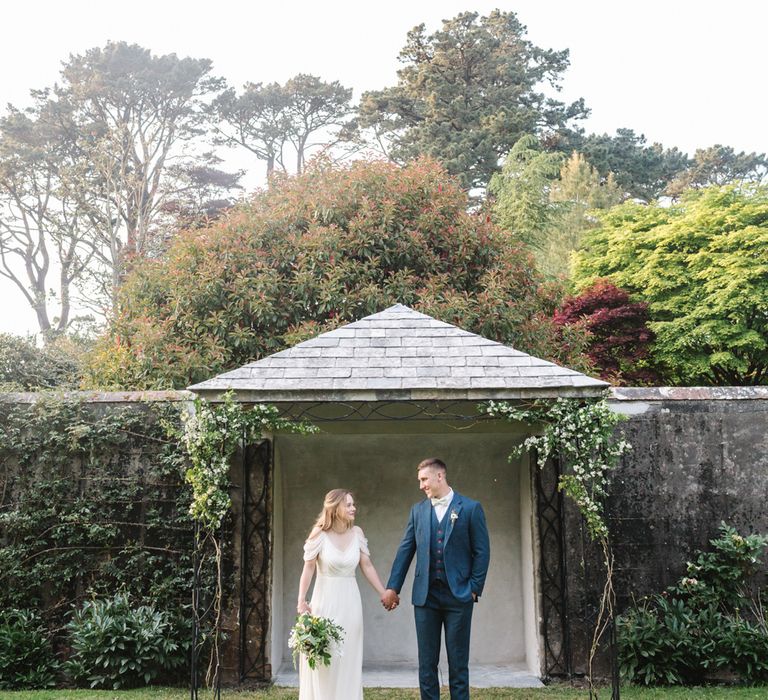 Bride in Bardot Shoulder Rock The Frock Bridal Gown via The Wedding Hub | Groom in Navy Blue Wool Three Piece Suit The Vintage Suit Hire Company | Timeless English Country Garden Inspiration at Boconnoc House and Estate in Cornwall, Styled by On Serpentine Shores | Debs Alexander Photography