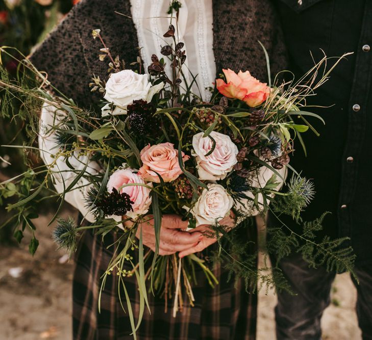 Wild wedding bouquet with roses and foliage