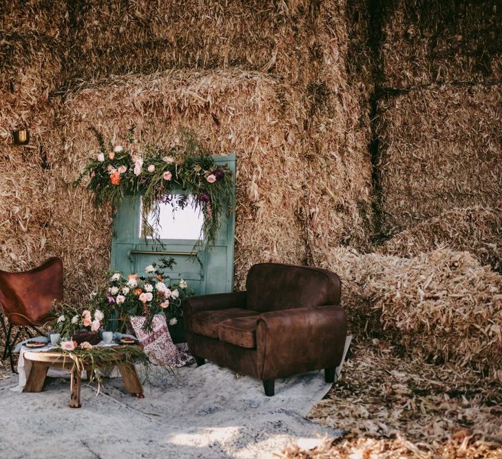 rustic seating area with leather chairs, flowers and hay bales