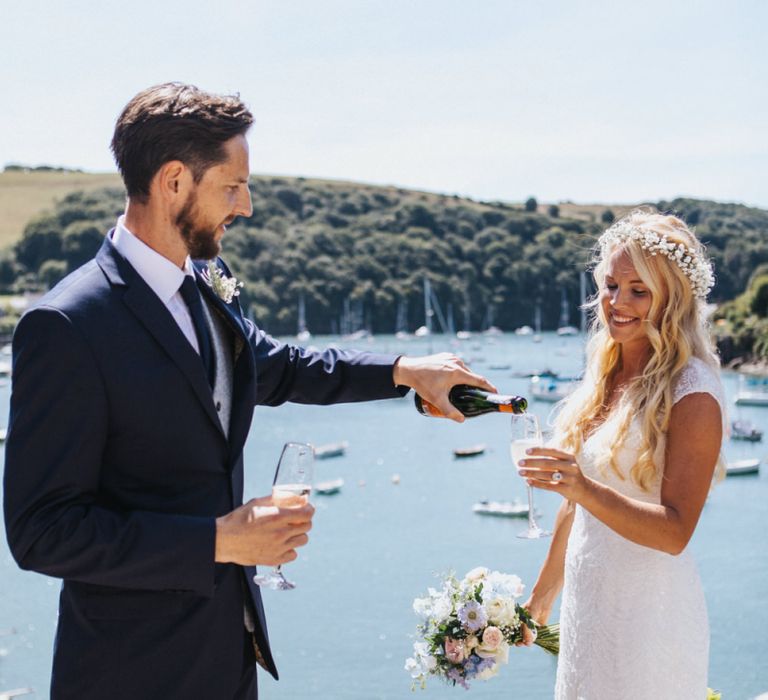 Bride in Sophia Tolli Galene Wedding Dress and Groom in Navy Blue Ted Baker Suit Toasting by the Dock