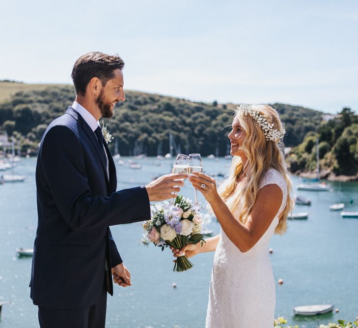 Bride in Sophia Tolli Galene Wedding Dress and Groom in Navy Blue Ted Baker Suit Toasting by the Dock