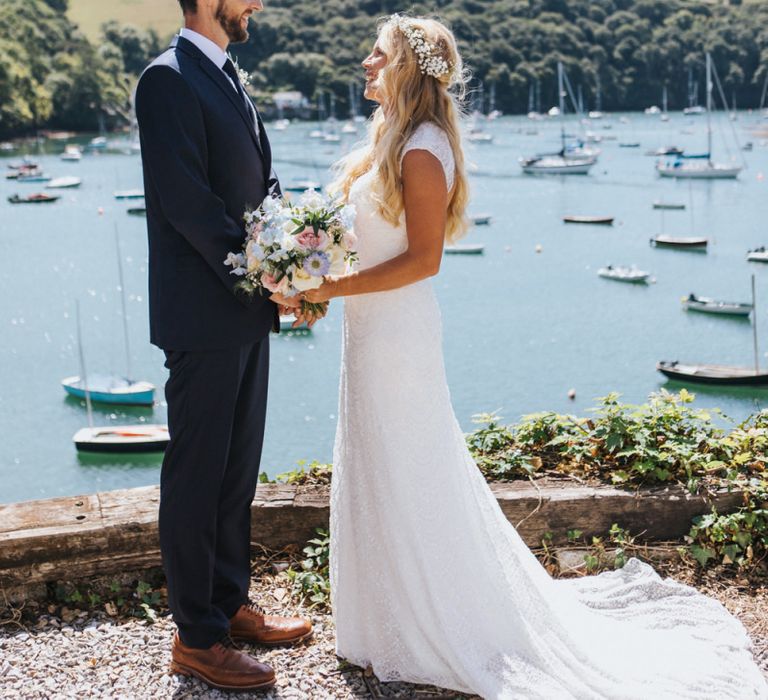 Bride in Sophia Tolli Galene Wedding Dress and Groom in Navy Blue Ted Baker Suit Embracing by The Marina