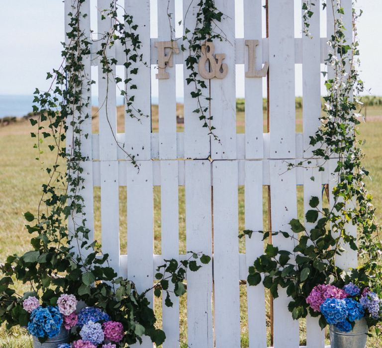 Wooden Pallet Backdrop Covered with Ivy and Buckets Filled with Pink and Blue Hydrangeas