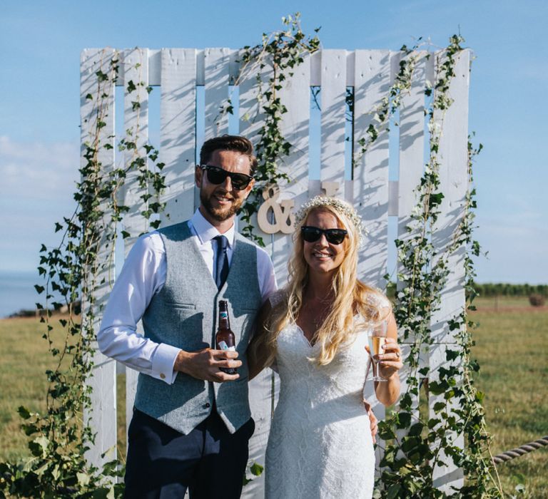 Bride in Sophia Tolli Wedding Dress and Groom in Grey Waistcoat Posing in Front of Palette Backdrop