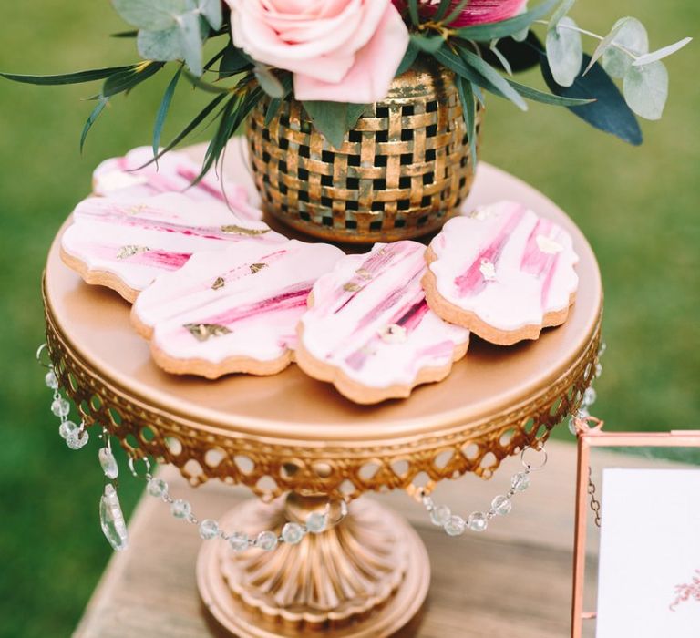 Pink Iced Wedding Biscuits and Floral Arrangement on Gold Cake Stand