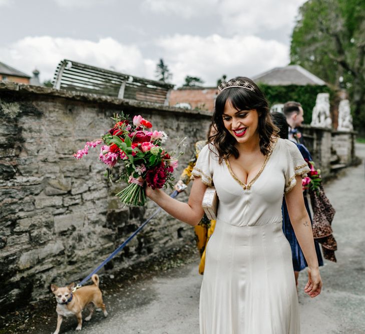 Beautiful Bride in Nude Vintage Wedding Dress with Gold Trims Wearing a Crown and Holding a Bright Wedding Bouquet