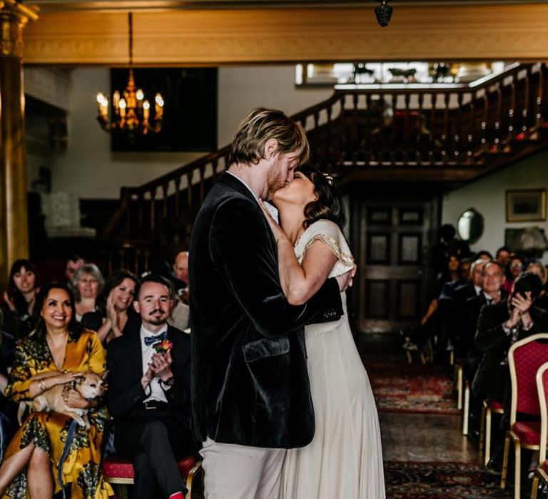 Wedding Ceremony at Walcot Hall with Bride in Vintage  Wedding Dress with Gold Trims and Groom in Velvet Blazer Kissing