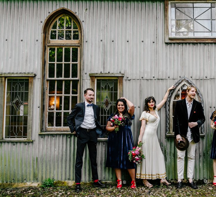 Stylish Wedding Party with Bridesmaids in Navy Velvet Dresses and Red Shoes, Bride in Vintage Wedding Dress and Groomsmen in Trousers and Blazers