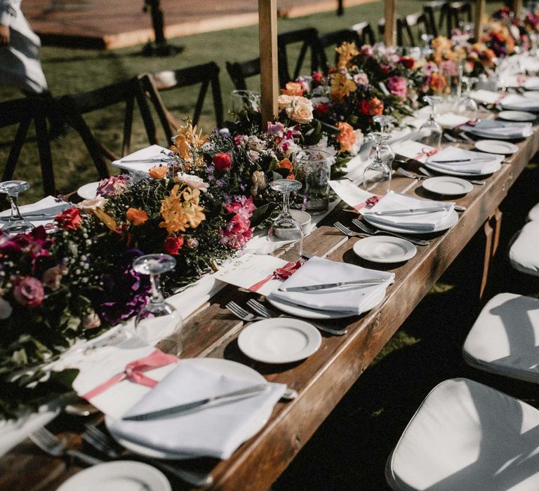 Bright pink and orange wedding flowers line the tables