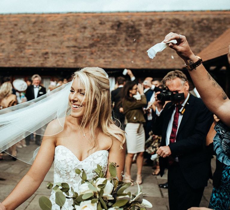 Bride clutching large bouquet with veil at Long Furlong Barn