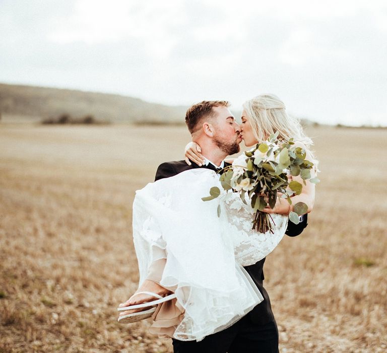 Groom lifts bride wearing flip flops