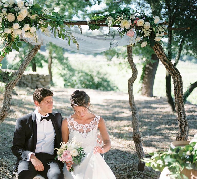 Floral Arch | Elegant Bride in Lace Wedding Dress | Groom in Black Tie Suit | Outdoor Wedding at Commanderie de Peyrassol, Provence, France Styled by La Chuchoteuse | Lace Bridal Gown | Black Tie Suit | Rustic Stretch Tent Reception | Raisa Zwart Photography