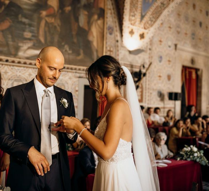 Bride and groom exchange vows with bride wearing Justin Alexander wedding dress