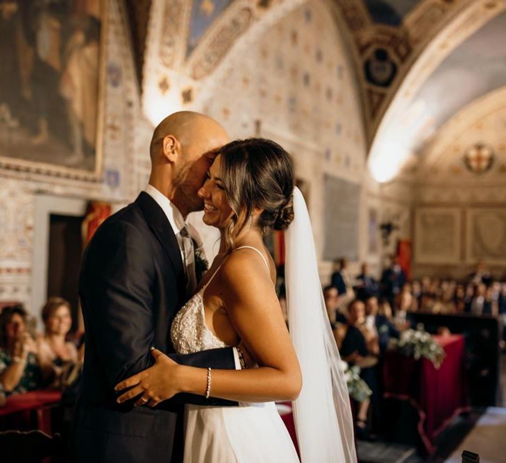 Bride and groom exchange vows with bride wearing Justin Alexander wedding dress