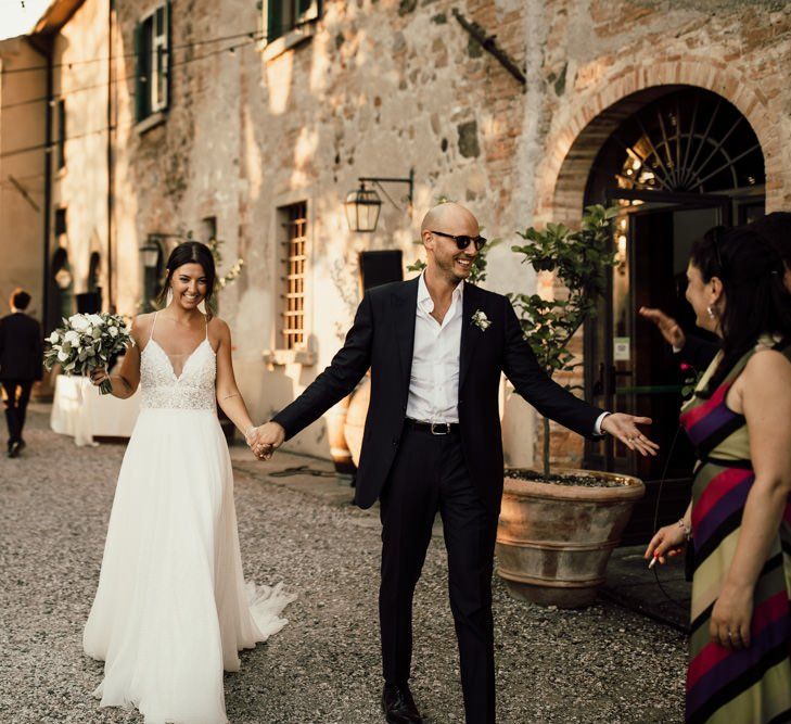 Bride in thin strap Justin Alexander wedding dress and groom enter reception