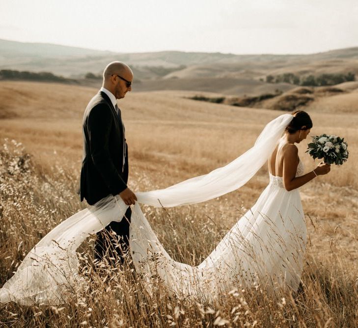 Justin Alexander wedding dress with long veil and groom in black suit