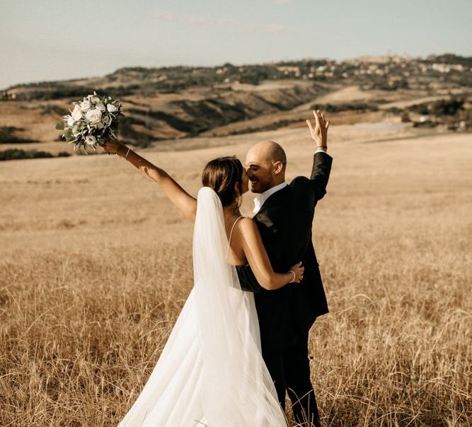 Bride wears Justin Alexander wedding dress with groom in black suit