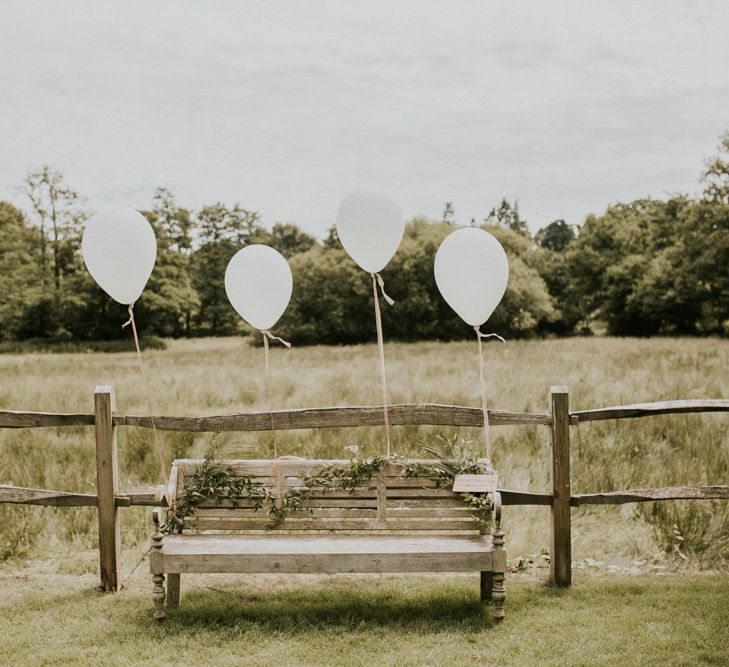 Wooden Bench with Giant Balloon Decor &amp; Greenery Garland | Millbridge Court, Surrey Wedding with DIY Decor, Foliage &amp; Giant Balloons | Nataly J Photography