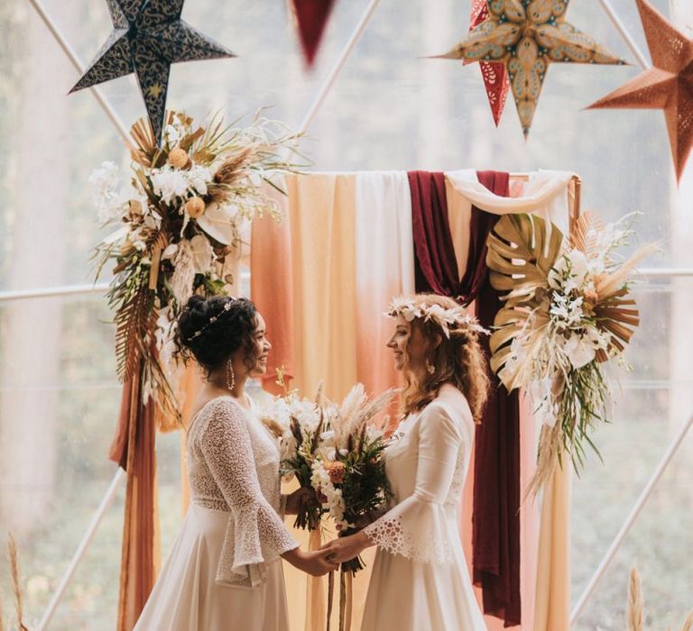 Boho Brides Standing at the Altar in Rolling In Roses Wedding Dresses in Geometric Dome