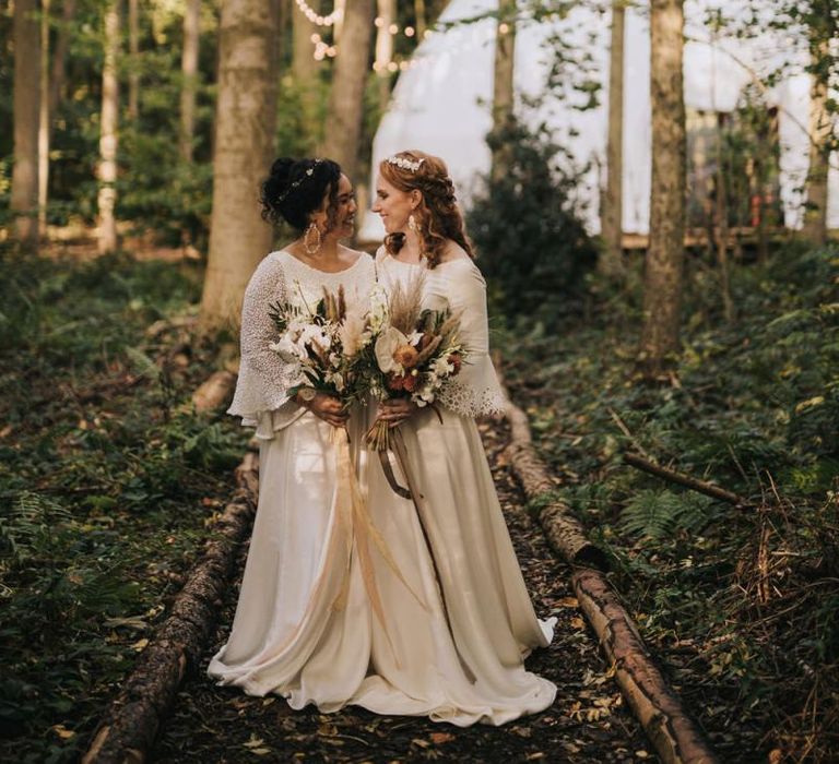 Boho Brides Standing in Camp Katur's woodland with the Geometric Dome Backdrop