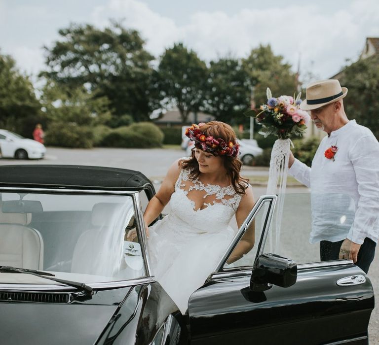 Bride in Lace Wedding Dress and Colourful Bridal Crown Getting into the Wedding Car