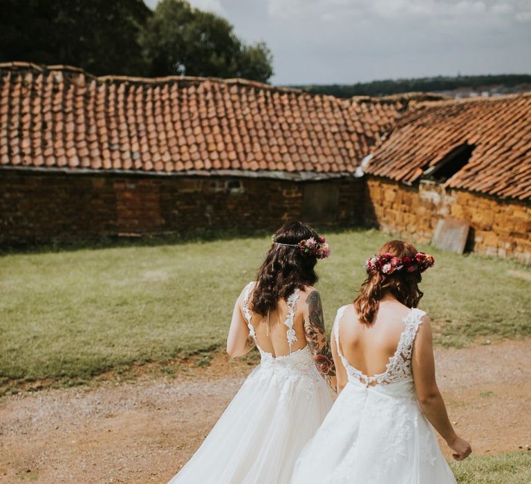 Two Brides in Lace Bow Back Wedding Dresses and Colourful Flower Crowns