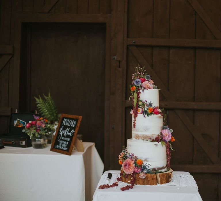 Semi Naked Wedding Cake on a Tree Slice Cake Stand Decorated with Wedding Flowers