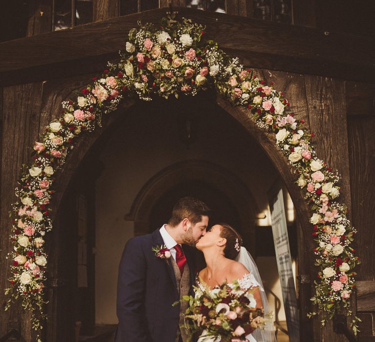 Church Floral Arch Wedding Flowers | Bride in Lillian West Bridal Separates | Groom in Navy Suit &amp; Tweed Waistcoat | Burgundy &amp; Gold Winter Wedding at Ramster Hall Weddings, Surrey | Matt Penberthy Photography | John Harris Wedding Films