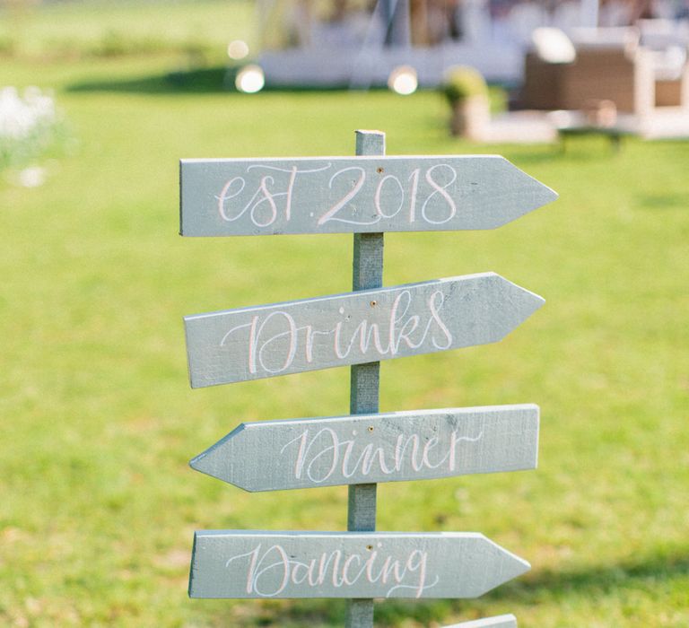 Wooden directional signage | Papakata Sperry Tent Wedding at family home | Sassi Holford Dress with added ivory Ostrich feathers to veil | Manolo Blahnik shoes | Images by Melissa Beattie