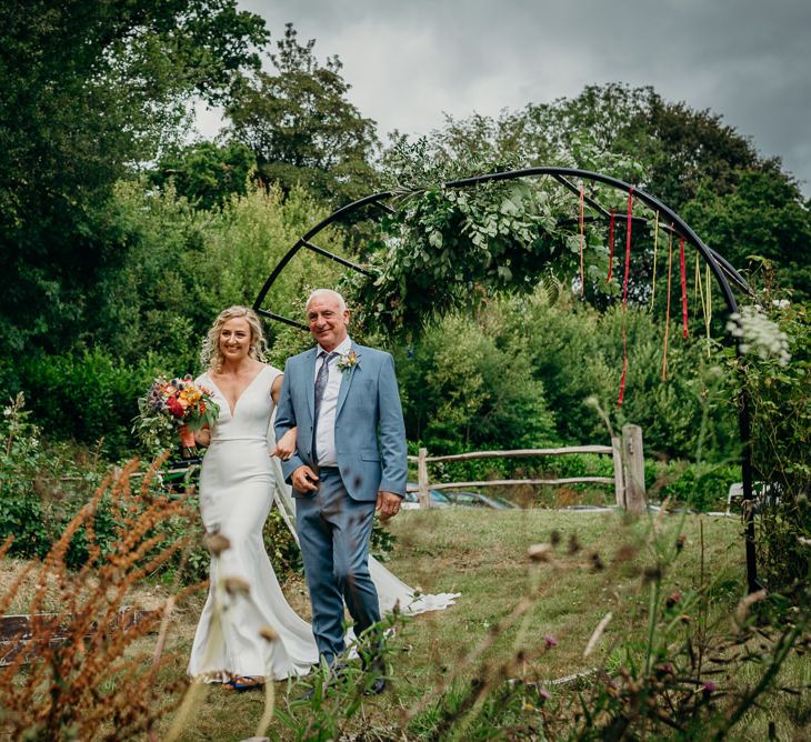 Bride makes her way to ceremony with bright wedding decorations and bouquet