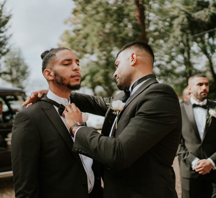 Groomsmen adjust their bow ties