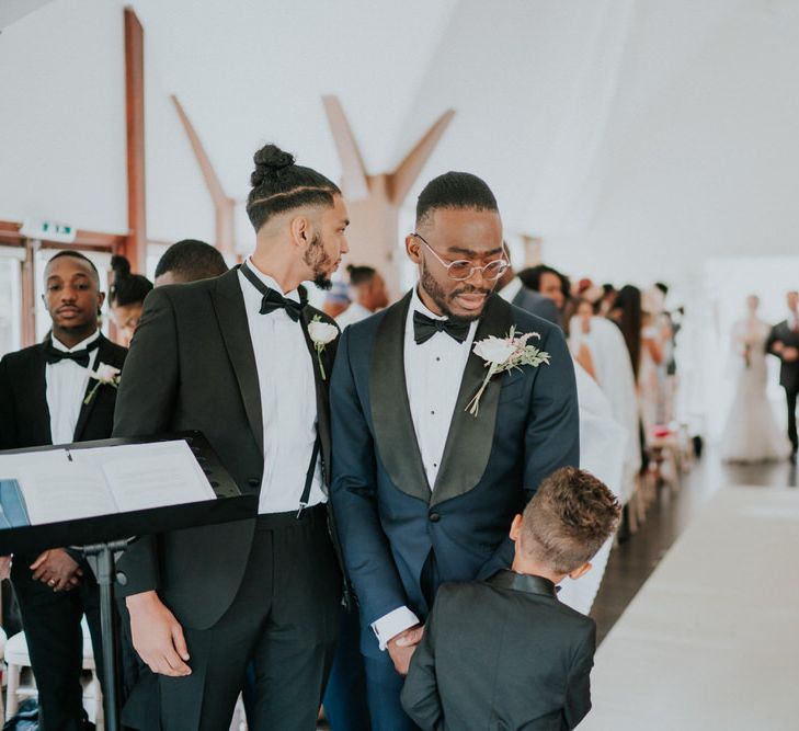 Groom in navy tuxedo and son at the altar waiting for the bride to enter