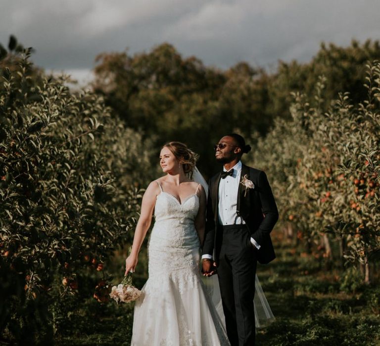 Bride in Morilee wedding dress and groom in tuxedo standing in a field