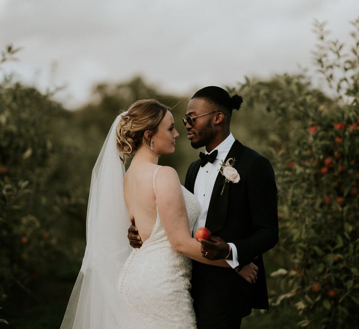 Bride and groom portrait in an orchard with bride in Morilee wedding dress