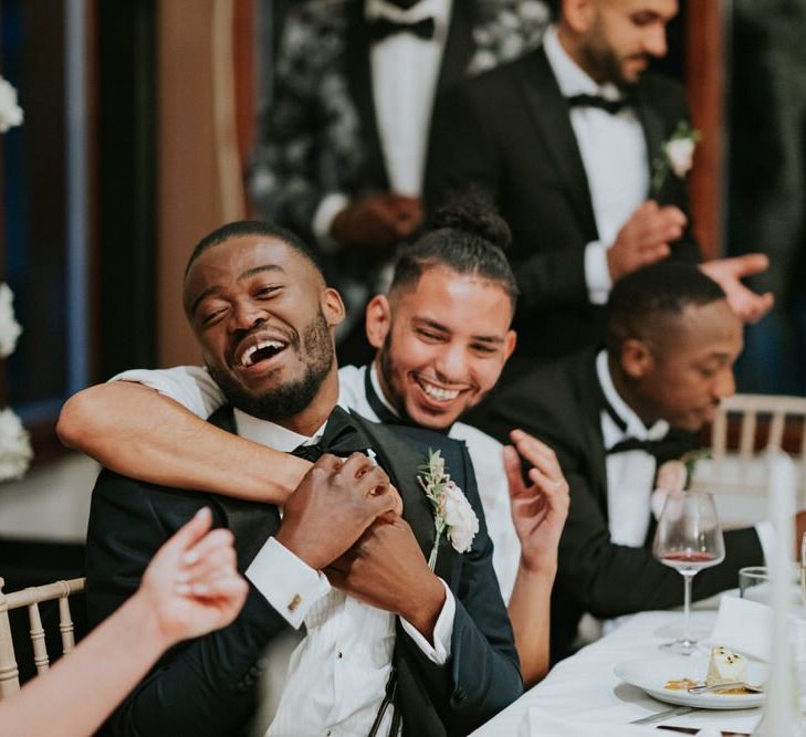 Groom and best man hugging at wedding reception