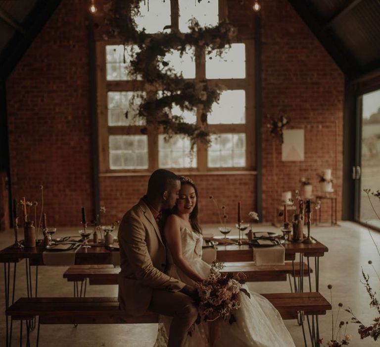 Groom embracing his bride in an embroidered wedding dress at the Giraffe Shed