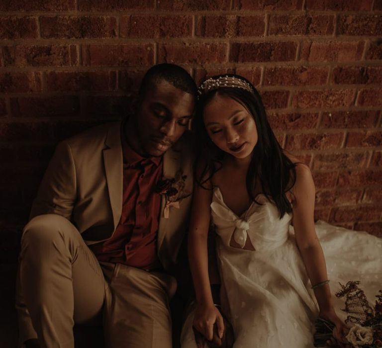 Bride and groom sitting by the wall at the Giraffe Shed