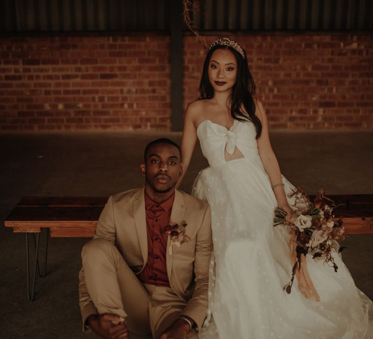 Portrait of groom in beige suit and burgundy shirt and bride in E&amp;W Couture wedding dress at the Giraffe Shed