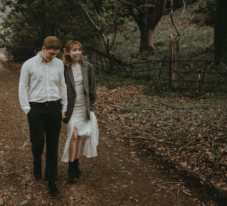 Bride and Groom Walking Through The Woodland Holding Hands