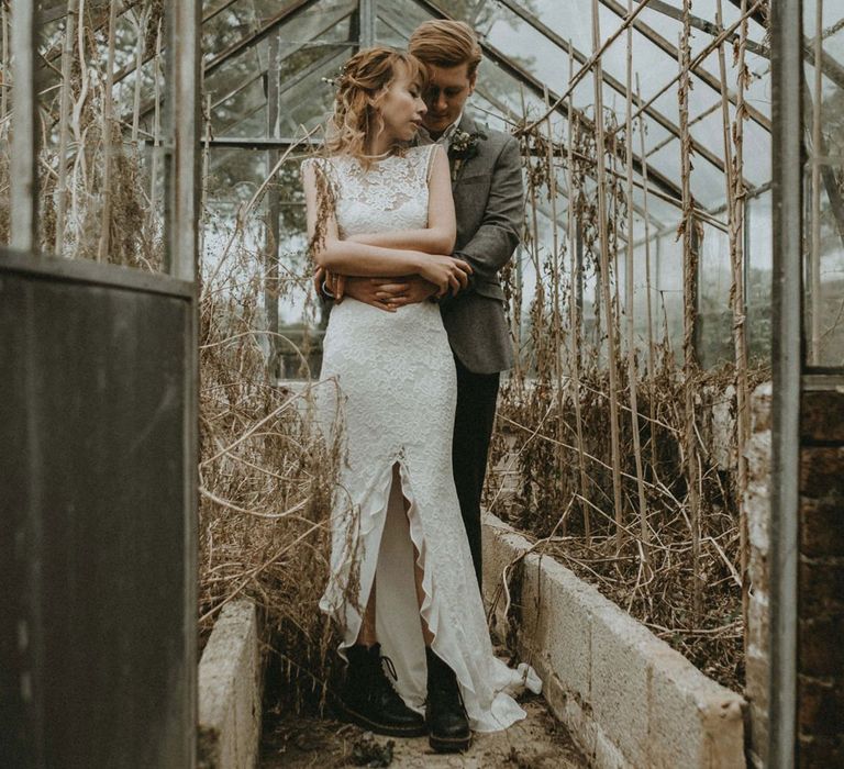 Groom Embracing His Bohemian Bride in Lace Wedding Dress with Front Split and Boots