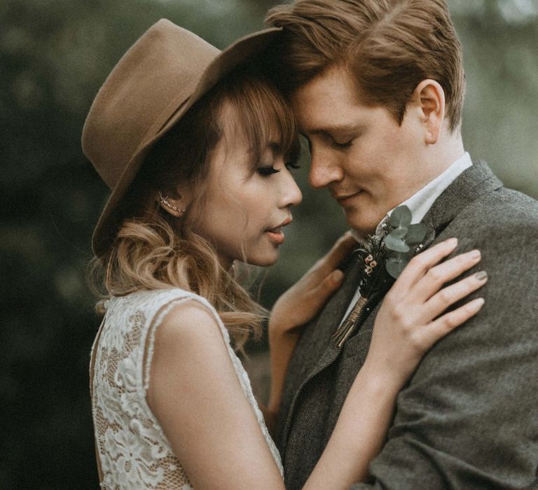 Bride in Lace Wedding Dress and Felt Hat and Groom in Wool Blazer Embracing