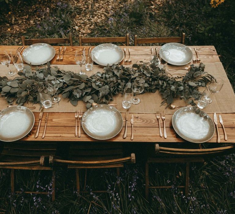 Wooden Table with Greenery Runner and Gold Cutlery