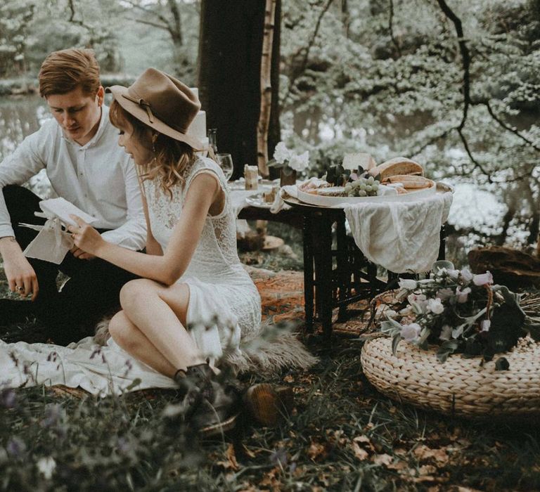 Boho Bride in Lace Wedding Dress and Felt Hat and Groom in White Shirt   Reading Wedding Vows